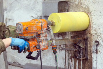 Worker using an electric drill to make a hole in a concrete wall, closeup. - 793713091