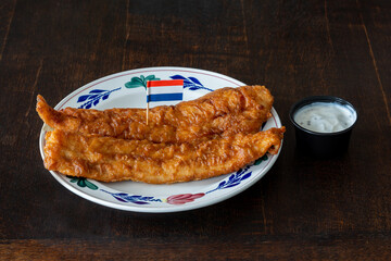 Lekkerbek with sauce on the plate decorated with dutch flag, deep fried fish fillet and a typical...