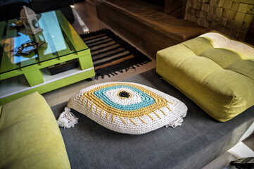 Detail of modern interior design in living room.Stylish grey sofa adorned with vibrant green pillows, including one eye-shaped pillow positioned centrally, adding whimsical touch to contemporary decor