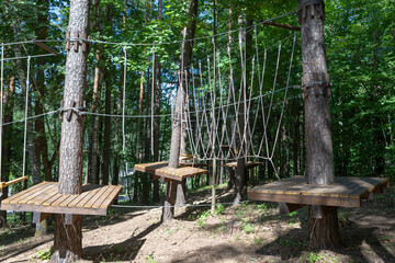 Naklejka premium Rope park. Rope ladders. Summer activity. Sport. Children's playground in nature in the forest.