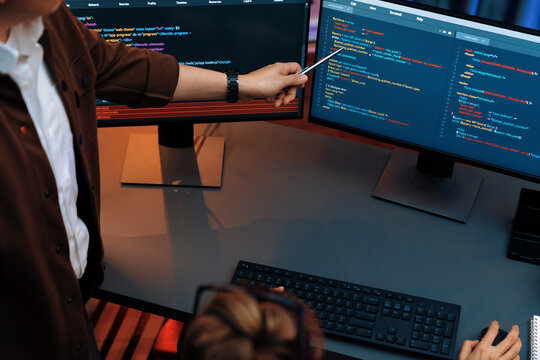 Top view of IT developers discussing with point to intelligent website development coder system running data online two screens information technology at neon light room at modern office. Infobahn.