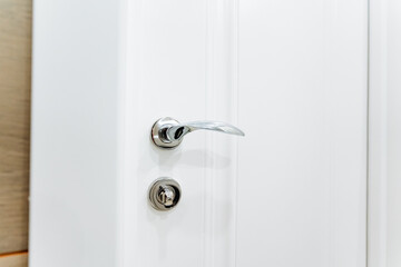 Chrome door hardware elements, silver handle, lock on the door to the room.