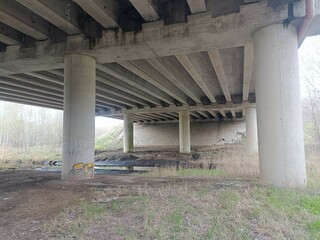 Concrete bridge and river. Concrete bridge. Small river floating under the bridge. Grass and trees around. Cloudy day. Countryside.