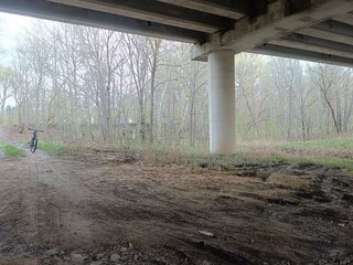 Concrete bridge and river. Concrete bridge. Small river floating under the bridge. Grass and trees around. Cloudy day. Countryside.