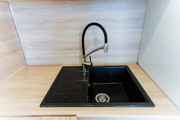 Rectangular black kitchen sink with faucet on wooden countertop
