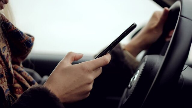 Woman writing message in vehicle on social network chats on cellphone	
