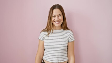 Delighted young woman with blue eyes and a toothy smile standing confidently, exuding positivity over a pink isolated background