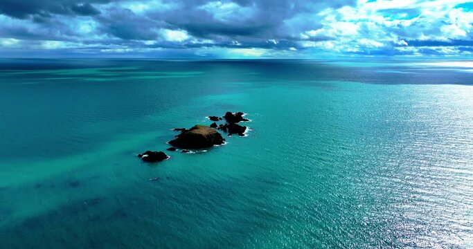 Drone flying to islands with emerald green sea and dramatic skyline on the Copper Coast in Waterford Ireland in spring dramatic establishing shot