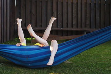happy kids relaxing in a hammock outdoor. children's feet barefoot. Holidays vacation