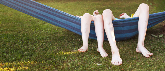 happy kids relaxing in a hammock outdoor. children's feet barefoot. Holidays vacation.banner.