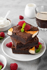Cheesecake brownies with raspberry on a gray concrete background. Delicious dessert