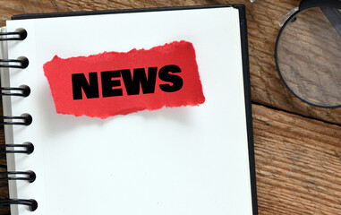 NEWS word written on a red piece of paper placed on a wooden table.