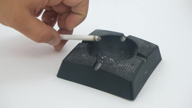 A white cigarette burning on a black ashtray