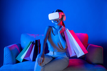 Smart female sit on sofa beside bags wear VR headset connecting metaverse, future cyberspace...