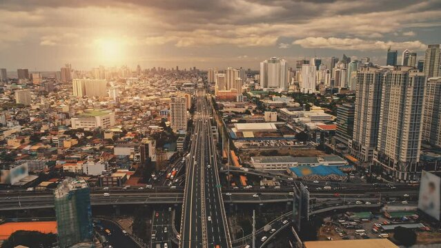 Cityscape at sun light with cross highway, streets, skyscrapers aerial. Bridge traffic road with driving cars at summer sunny day. Philippines capital cityscape of Manila town at drone shot