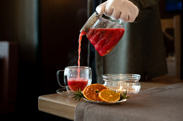Inviting author berry tea in a glass pot, warmed by a candle, with a clear cup and citrus accents...
