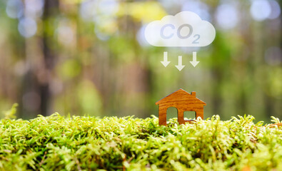 Reduce CO2 emission concept. A figurine of a house in the forest and a CO2 emission sign