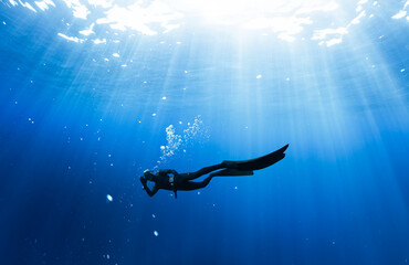 Freediver Swimming in Deep Sea With Sunrays.