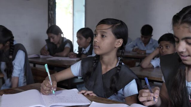 Rural Indian school students study in classroom. Elementary boys and girls writing doing classwork, test or exams, Education in india concept