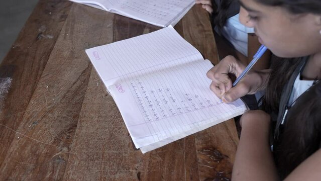 Indian school students study in classroom solve math sum on notebook. Elementary girls write doing classwork, test or exams, Education in india concept