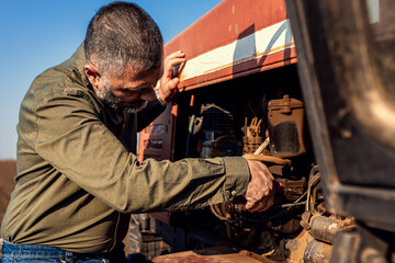 Farmer makes repairs on the tractor in the agricultural field.
