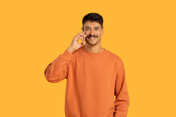 Man in Orange Sweater Talking on Cell Phone