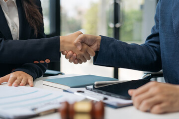 Middle age partner lawyers attorneys shaking hands after discussing a contract agreement done.