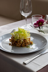 Cold Pork and Beans Salad with Escarole at Restaurant Table - Fine Dining Food and Drink in Elegant Setting