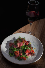 Succulent medium-rare steak slices, fresh salad with beets, ripe tomatoes, and an elegant drizzle of dressing.