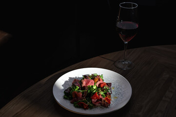 Succulent medium-rare steak slices, fresh salad with beets, ripe tomatoes, and an elegant drizzle of dressing.