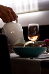 Waiter Pouring Cream Soup at Restaurant Table - Fine Dining Service Scene in Elegant Setting © AReniuValdes