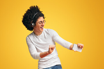 Active carefree black guy in wireless headphones enjoying music