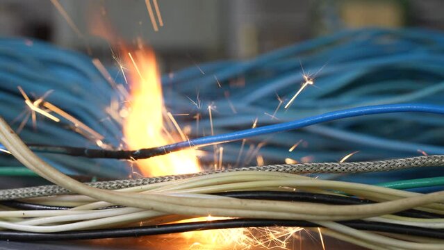 Flames, sparks, smoke between electrical cables, close up. Short circuit in the twisted wires from the electrical devices, fire hazard concept