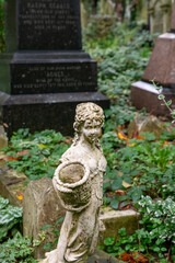 kleine Mädchenfigur mit Blumenkorb auf dem Highgate Cemetery in London Camden