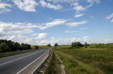 rural landscape with a road and a blue sky with white clouds