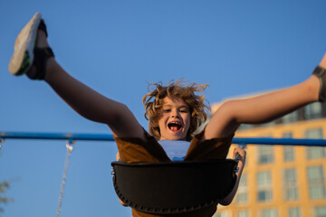 Kid swinging on swing in city park. Childhood, Freedom, Happy, Summer Outdoor. Cute child boy...