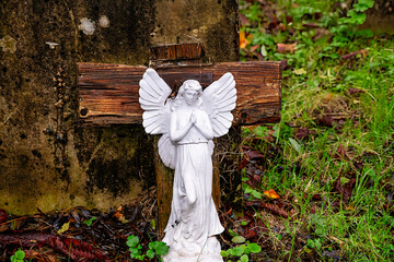 schöner kleiner weißer Engel vor einem Holzkreuz auf dem Highgate Cemetery in London Camden