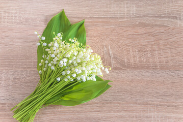 Happy May day greeting card; Bouquet of lileis of the valley on a wooden background; copy space