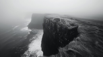 black and white photo of a cliff edge overlooking a foggy ocean - obrazy, fototapety, plakaty