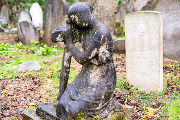 sehr alte kniende Frauenstatue auf dem Highgate Cemetery in London Camden
