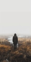 A person standing alone in a foggy field