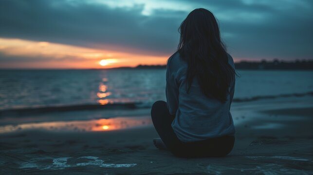 Young woman sitting beach sunset sea sand mental health thinking looking