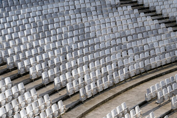 White seats in rows in empty amphitheatre auditorium outdoors. Empty seats in outdoor concert hall
