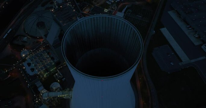 Aerial drone view on a fossil fueled power plant at dusk and night. Cooling tower exterioir. Duisburg, Germany. CLose up industrial installation.