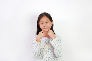 Portrait of young Asian girl child keeping fingers on corner of mouth isolated on white background. Child point at the part of body. - 793793416