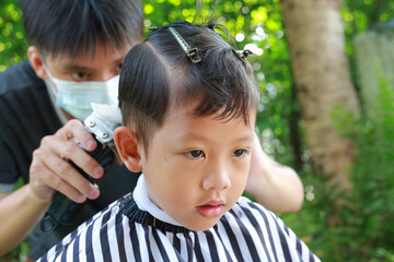 Cutting hair of Asian little boy with Hair Clipper in the garden - 793794427