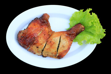 Roasted chicken leg on white plate isolated on black background. Top view. - 793794604