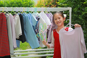 Asian girl hanging the laundry on a clothes rail at the garden near house.