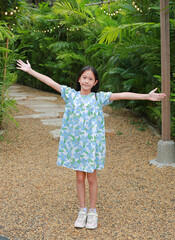 Pretty Asian girl arms outstretched or keeping arms raised while standing in the garden. - 793795495