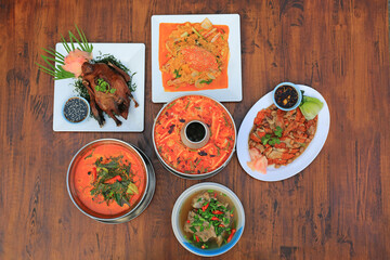 Varieties of Thai food on wooden table background. Tom Yum. Periwinkle curry. Pork bones soup. Stir fried crab. Sliced roast duck. Grilled Peking Duck. Top view. - 793795871